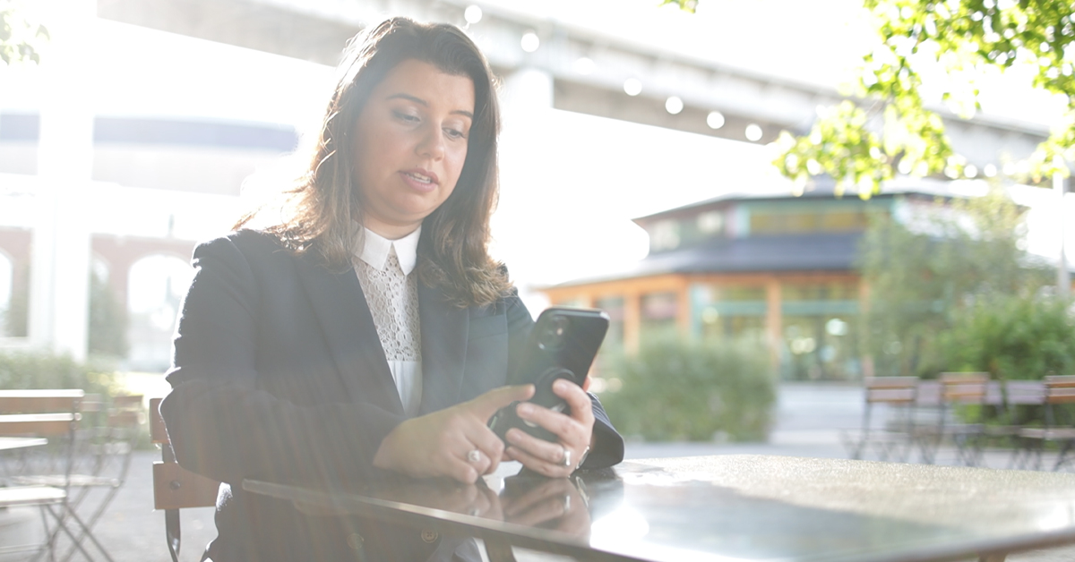 Female attorney sitting at table outside looking at phone