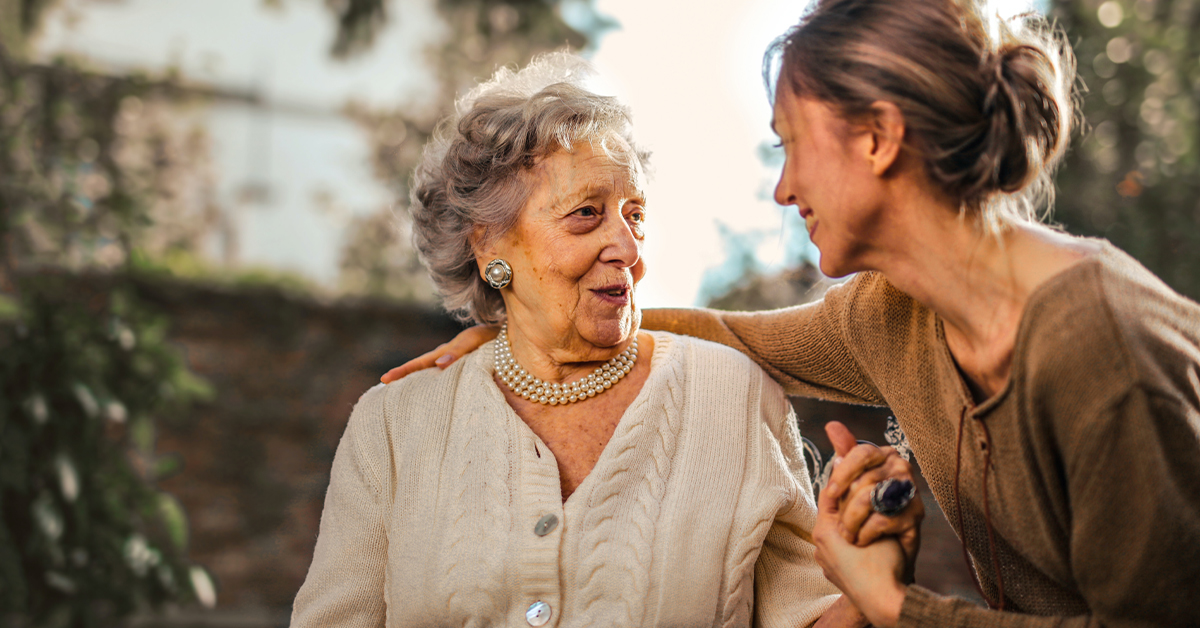 Smiling daughter with arm around her elderly mother